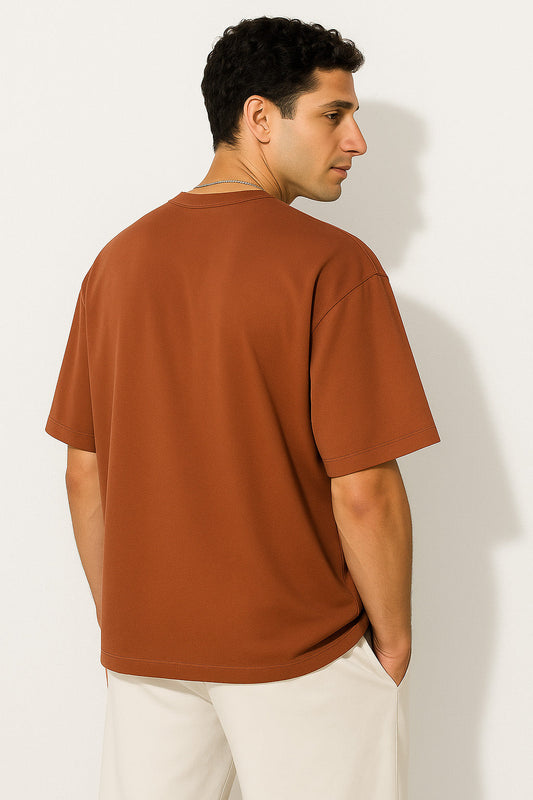 Angled back view of BANKAZ brown oversized eagle emblem t shirt showing relaxed silhouette