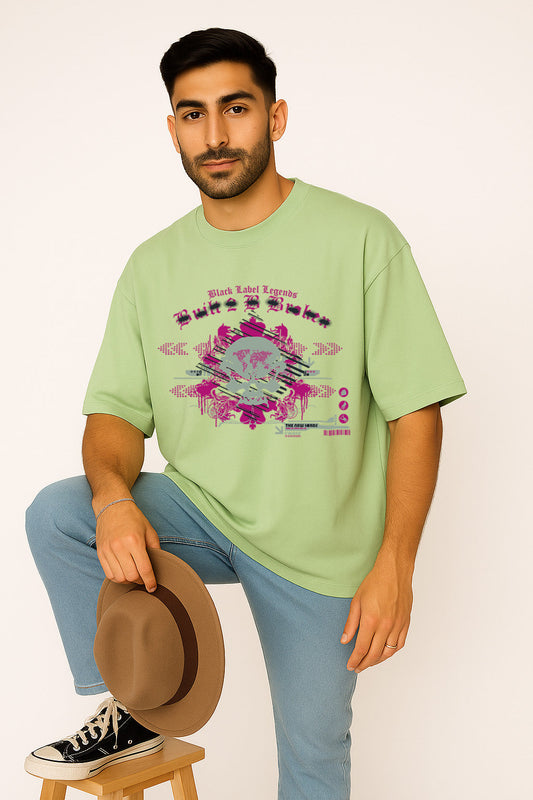 Seated pose showing BANKAZ gothic black label t shirt in green oversized style with bold front print