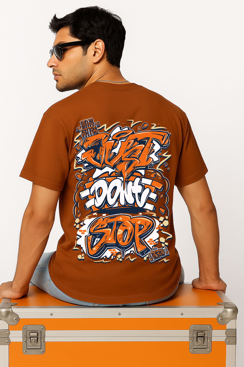 Seated back view of graffiti t shirt in brown oversized fit with bold street art "Just Don't Stop" print