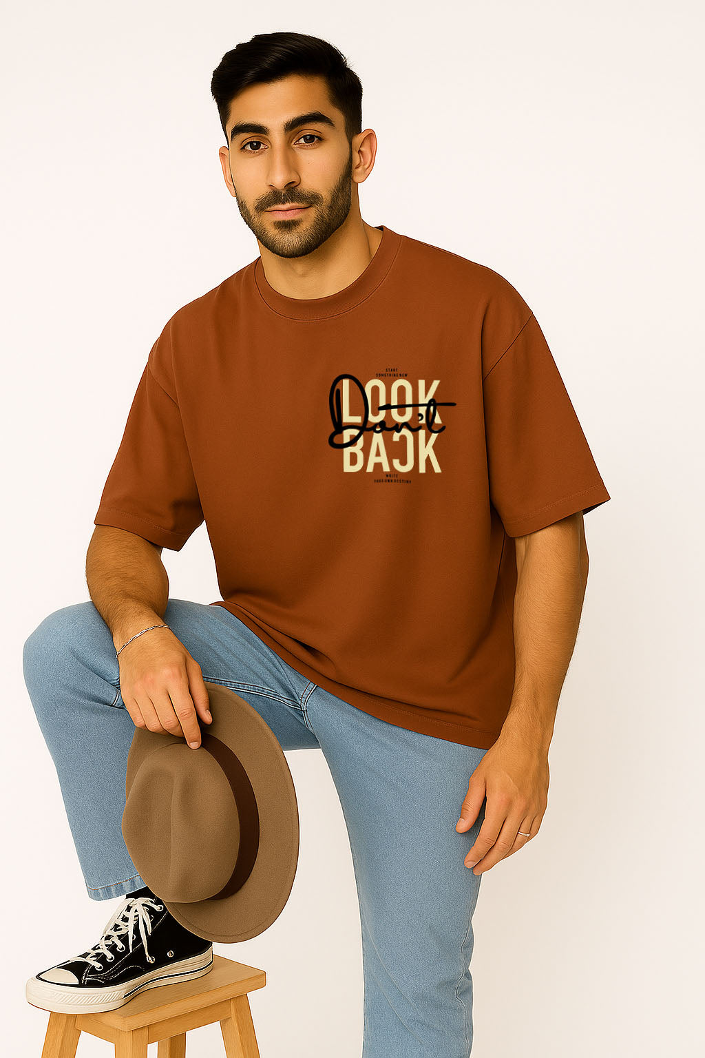 Brown oversized t shirt styled casually with hat, featuring minimal front graffiti slogan in focus
