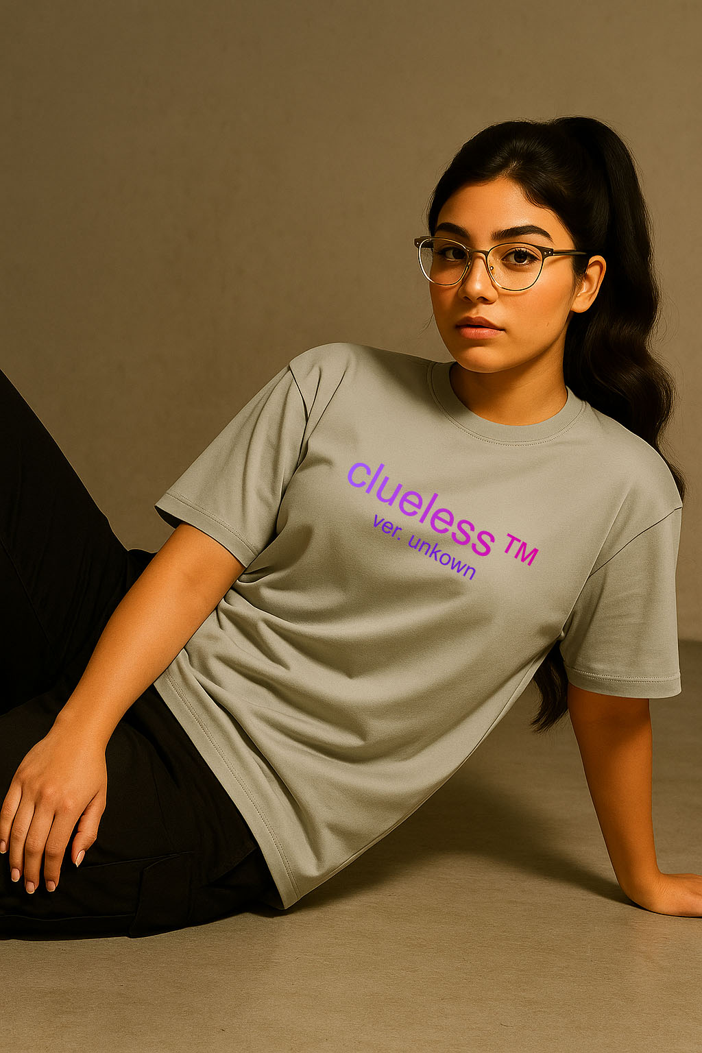 Reclining model in grey oversized t-shirt with “clueless” print – women’s aesthetic streetwear