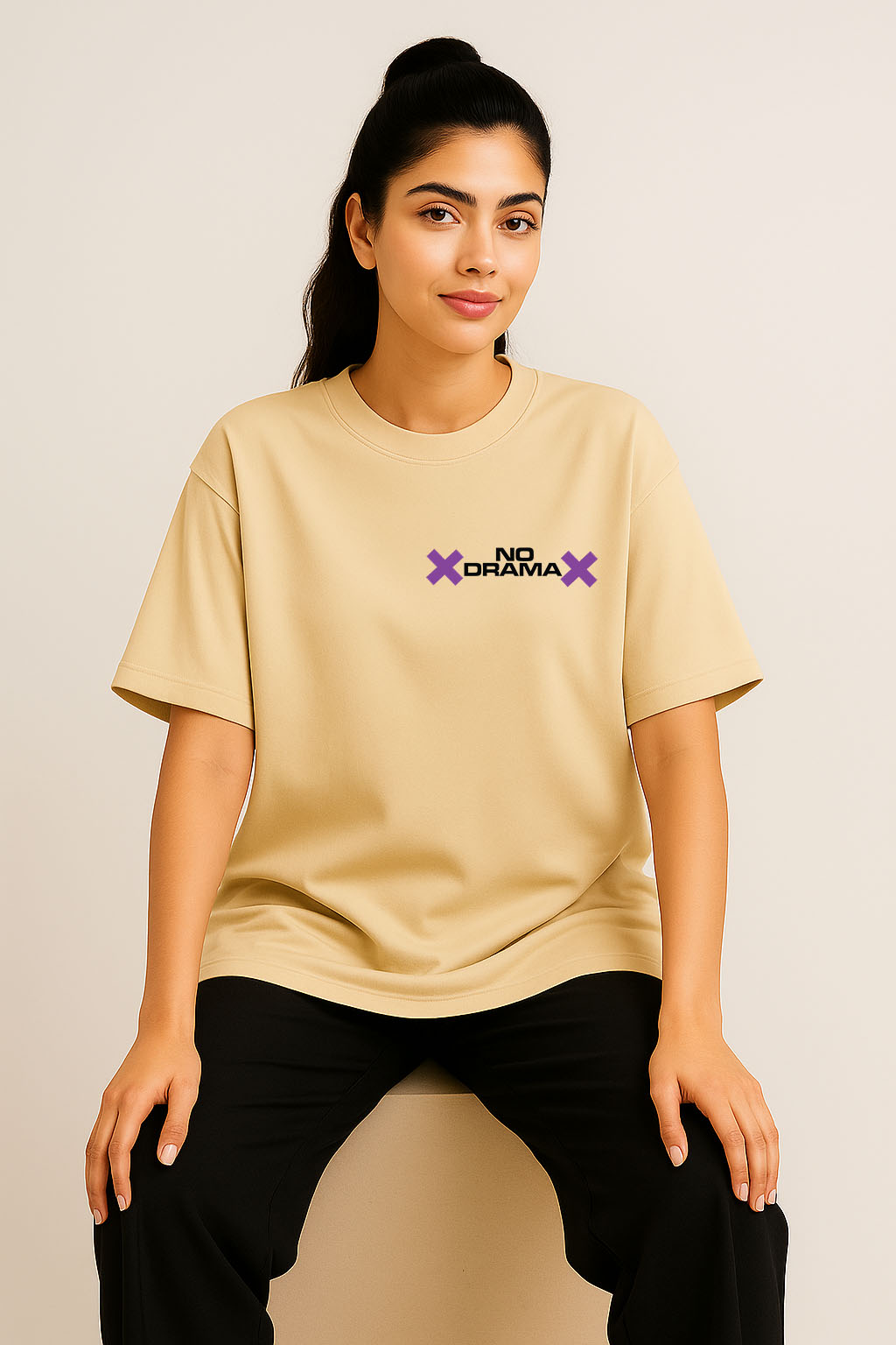 Sitting pose wearing off-white oversized t-shirt for women with front chest "No Drama" text