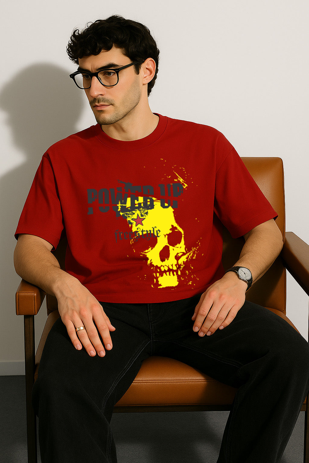 Seated model in BANKAZ red oversized skull t shirt with bold yellow skull graphic and "Power Up" text